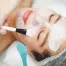 A cosmetologist does facial care and apply a face mask.