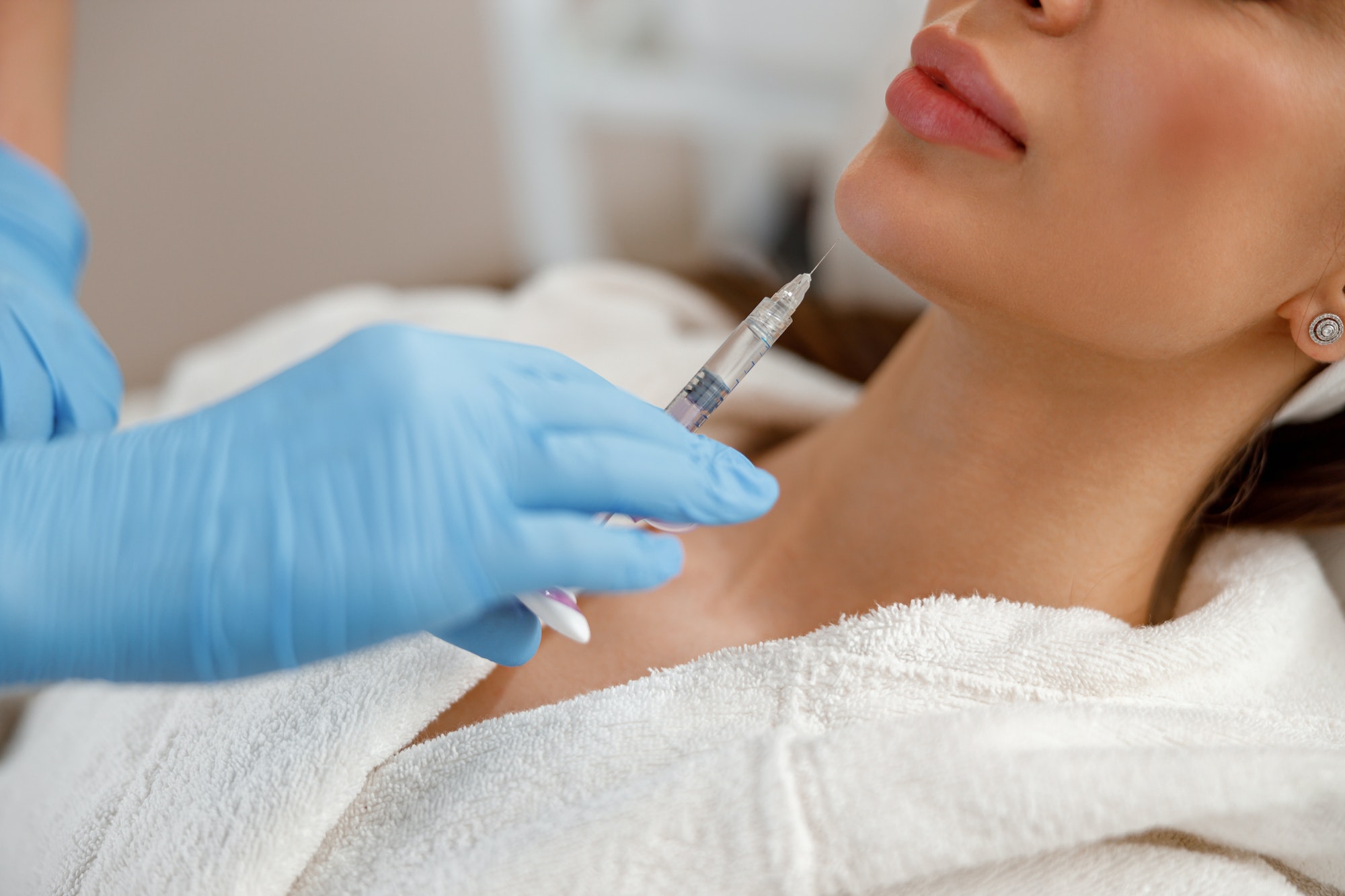 Closeup of young woman getting hyaluronic acid injections in chin at beauty salon